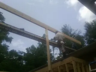 Carpenter setting a ridge beam over a new addition frame — Ice Dam Removal by Roofing Brothers in Mc Leansville