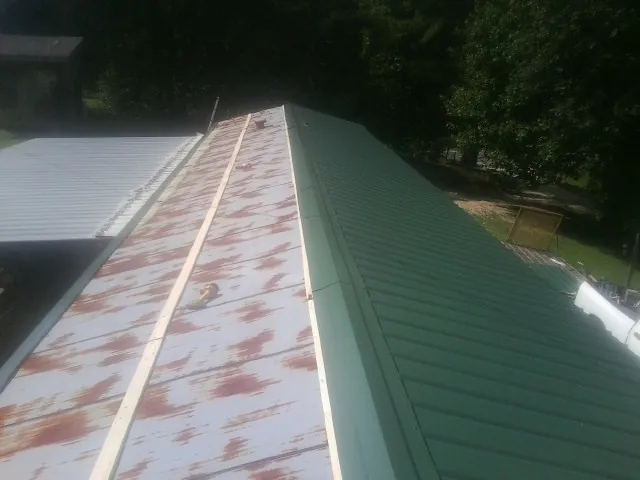 Old rusted panels beside newly installed green metal roofing — Wind Damage Roof Repair by Roofing Brothers in Mc Leansville