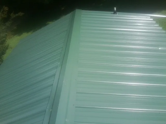 New green metal panels meeting at the ridge of a roof — Flat Roof Repair work by our crew in Mc Leansville