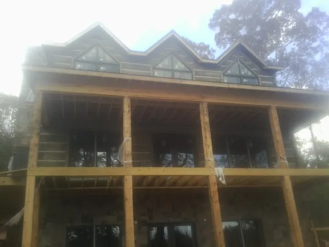 Dormers and porch framing on a large log home under construction — Roof Coating work by our crew in Mc Leansville