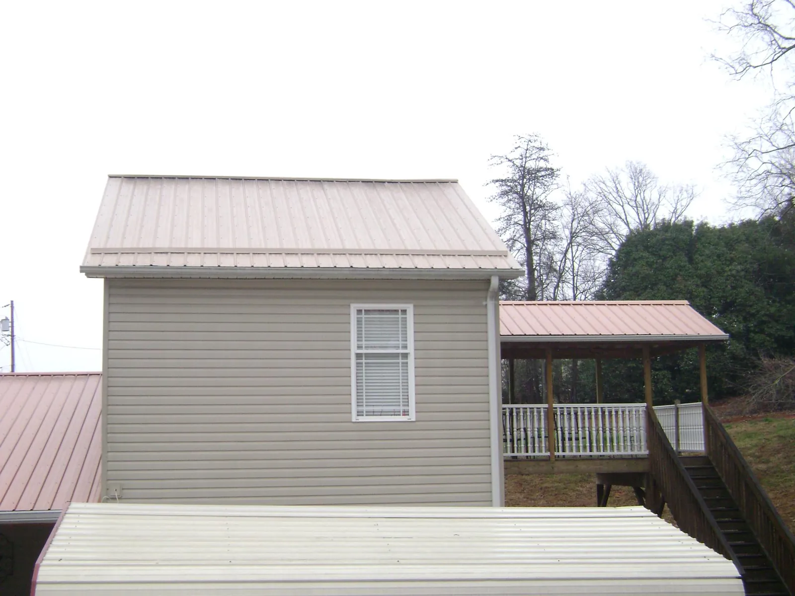 Tan metal roofs on a two story addition and attached porch, from a Roof Replacement job in Mc Leansville
