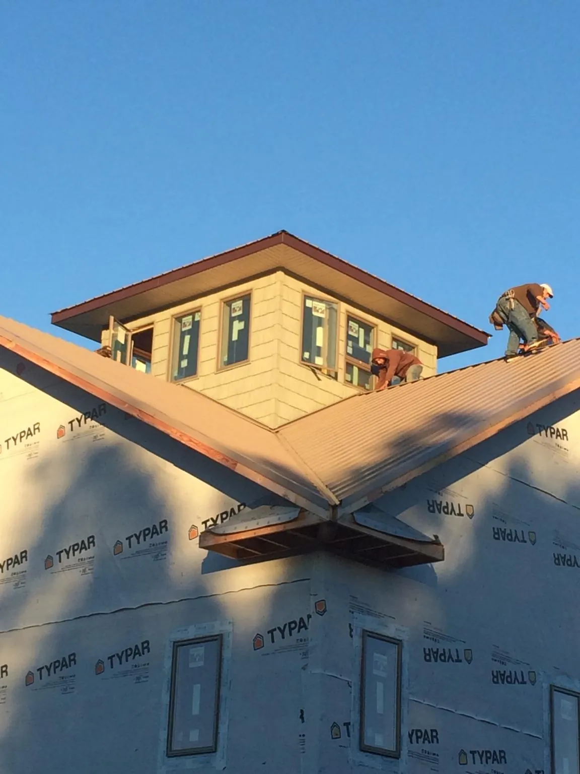 Roofers working around a rooftop cupola on a new metal roof at sunset — Roof Waterproofing in Mc Leansville by Roofing Brothers